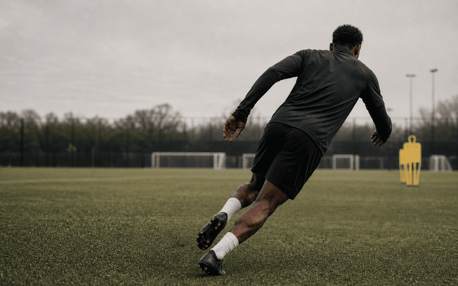 A footballer training alone on an open practice pitch.